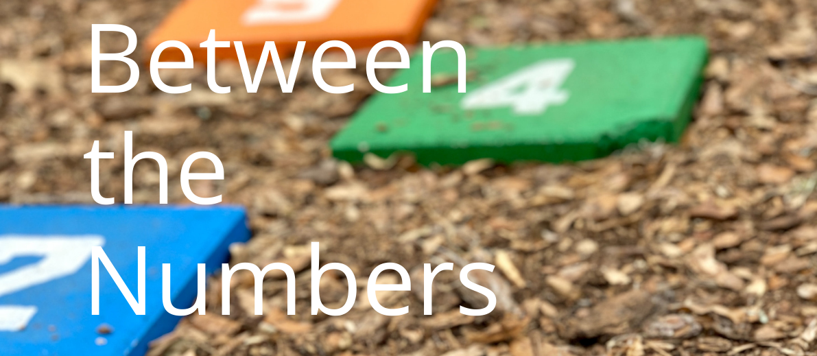 Between the Numbers banner with numbered squares on a wood chip background