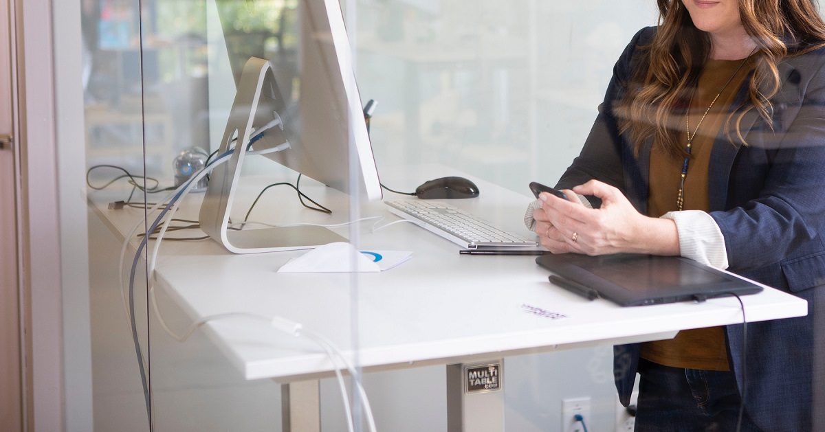 A closeup of a white desk with someone sitting at a computer