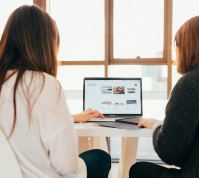 Two women at a desk looking at a laptop