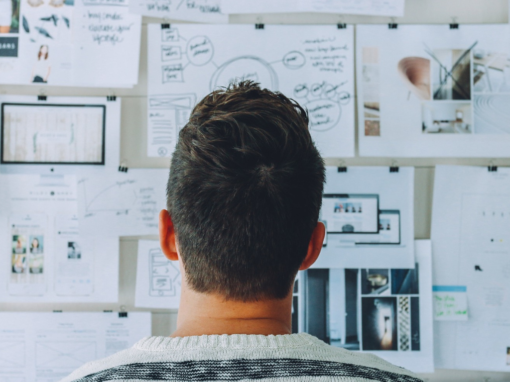 A man staring at a pin board with several documents