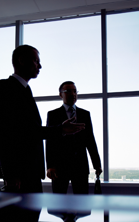 Two business people in an office darkened due to being infront of a bright window